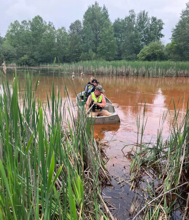 Men in canoe collecting data from the Dober Mine settling ponds